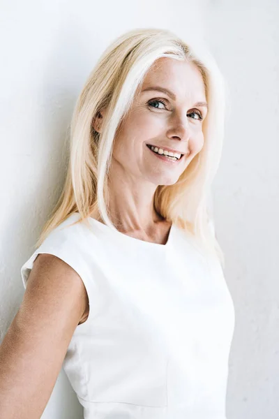 Happy blonde mature woman near white wall — Stock Photo