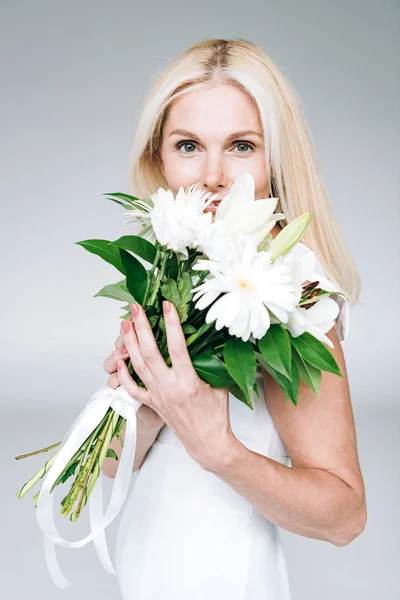 Mulher madura loira com flores brancas isoladas em cinza — Fotografia de Stock