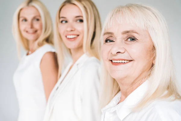 Foco seletivo de mulheres loiras de três gerações isoladas em cinza — Fotografia de Stock