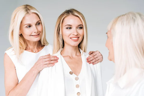 Три покоління блондинки в білому одязі ізольовані на сірому — стокове фото