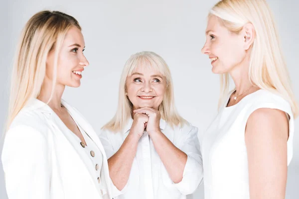 Blonde Mutter und Tochter stehen sich gegenüber, nahe der glücklichen Großmutter, isoliert auf grau — Stockfoto