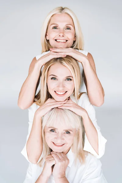 Hermosa sonrisa de tres generaciones mujeres rubias aisladas en gris - foto de stock