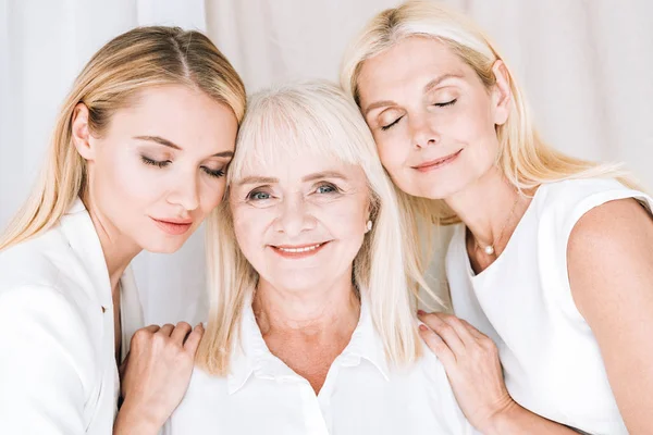 Heureux élégantes femmes blondes de trois générations dans des tenues blanches totales — Photo de stock