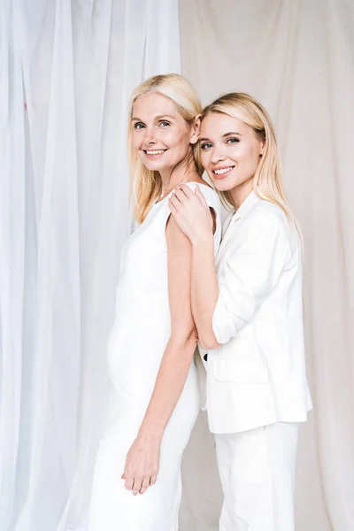 Side view of elegant blonde mother and daughter in total white outfits — Stock Photo