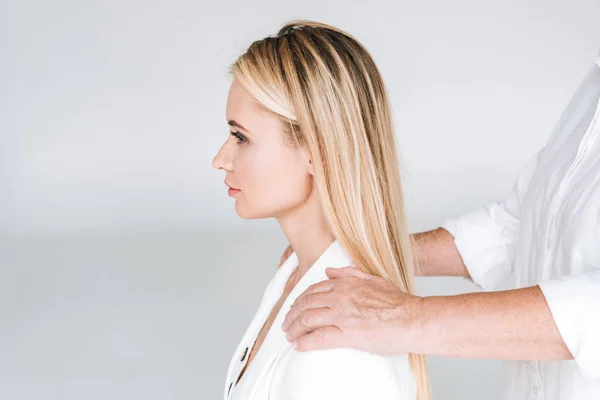 Seitenansicht der blonden Enkelin mit den Händen auf den Schultern isoliert auf grau — Stockfoto