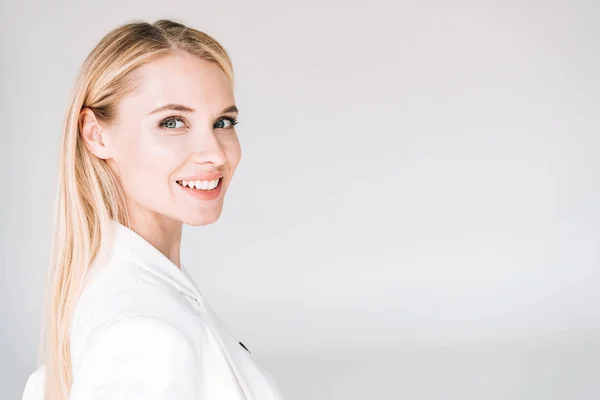 Lächelnd schöne junge blonde Frau isoliert auf grau — Stockfoto