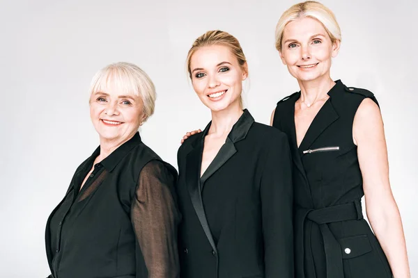 Mulheres loiras felizes de três gerações na moda em roupas pretas totais isoladas em cinza — Fotografia de Stock