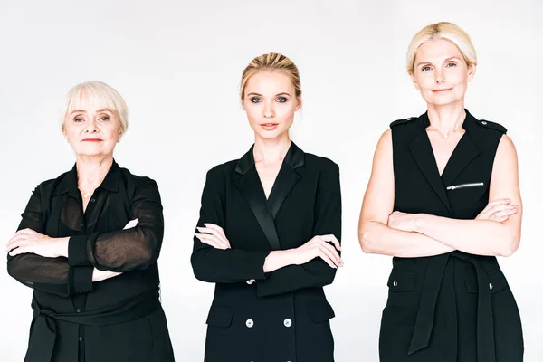 Donne bionde alla moda di tre generazioni in abiti total black con braccia incrociate isolate sul grigio — Foto stock