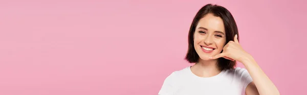 Tiro panorâmico de bela menina sorridente mostrando chamar-me gesto isolado em rosa — Fotografia de Stock