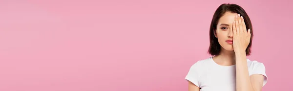Tiro panorâmico de menina bonita cobrindo rosto com a mão isolada em rosa — Fotografia de Stock