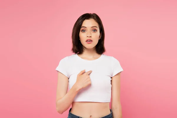 Beautiful surprised girl pointing with finger at herself isolated on pink — Stock Photo