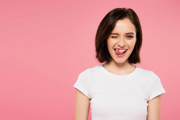 Hermosa chica mostrando lengua y guiño aislado en rosa - foto de stock