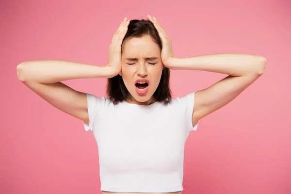 Beautiful girl with hands on head and closed eyes screaming isolated on pink — Stock Photo