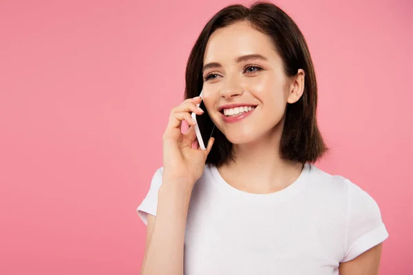 Hermosa chica sonriente hablando en el teléfono inteligente aislado en rosa - foto de stock