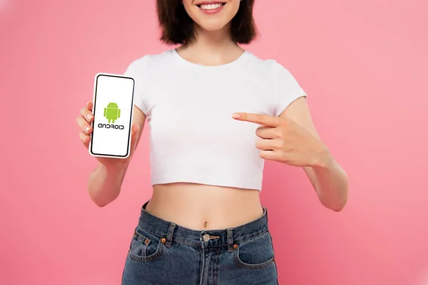 KYIV, UCRAINA - LUGLIO 3, 2019: vista ritagliata della ragazza che punta con il dito allo smartphone con logo Android isolato su rosa — Foto stock