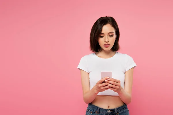 Beautiful girl chatting on smartphone isolated on pink — Stock Photo