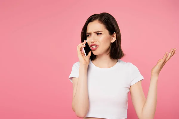 Chica disgustado hablando en el teléfono inteligente aislado en rosa - foto de stock