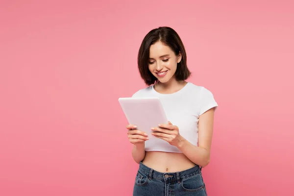 Belle fille souriante en utilisant tablette numérique isolé sur rose — Photo de stock