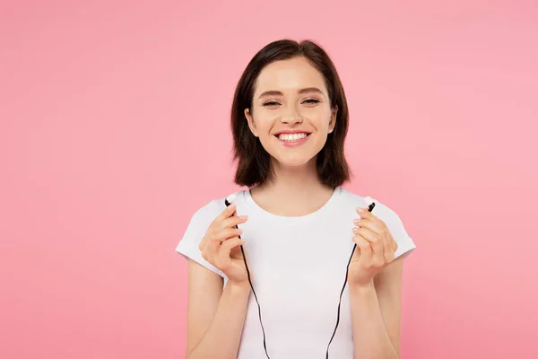 Sorridente ragazza in possesso di auricolari isolati su rosa — Foto stock