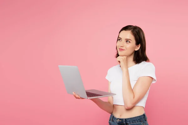 Dreamy smiling pretty girl using laptop isolated on pink — Stock Photo