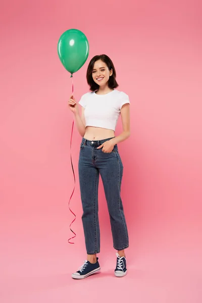 Visão comprimento total de sorrir menina bonita segurando balão verde isolado em rosa — Fotografia de Stock