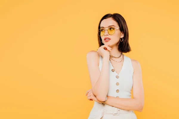 Мрійлива модна дівчина в сонцезахисних окулярах дивиться ізольовано на жовтому — стокове фото