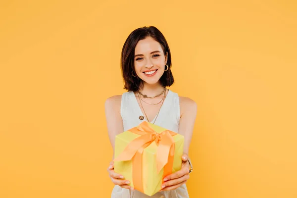 Happy smiling girl holding gift box isolated on yellow — Stock Photo