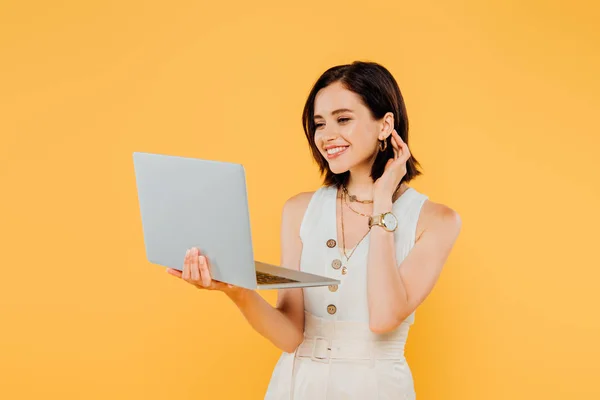 Sonriente chica elegante con portátil aislado en amarillo - foto de stock