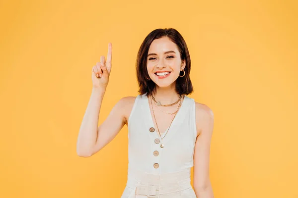 Sonrisa elegante chica mostrando idea gesto aislado en amarillo - foto de stock