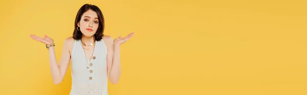 Plano panorámico de chica elegante confusa mostrando gesto de encogimiento aislado en amarillo - foto de stock