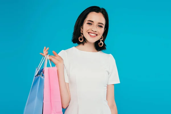 Mujer elegante sonriente en vestido con bolsas de compras aisladas en azul - foto de stock
