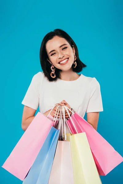 Smiling elegant woman in dress with shopping bags isolated on blue — Stock Photo