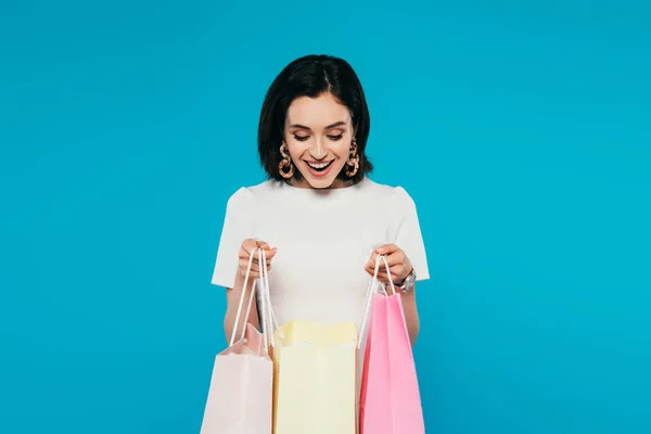 Excited elegant woman in dress holding shopping bags isolated on blue — Stock Photo