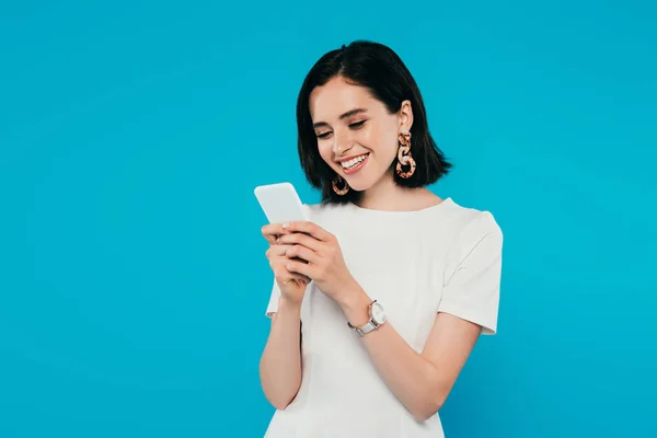 Smiling elegant woman in dress using smartphone isolated on blue — Stock Photo