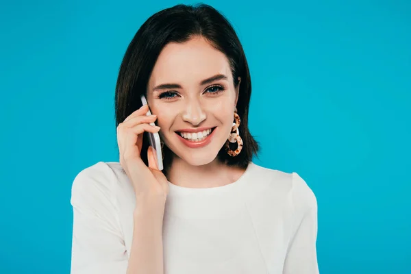 Sonriente mujer elegante en vestido hablando en teléfono inteligente aislado en azul - foto de stock