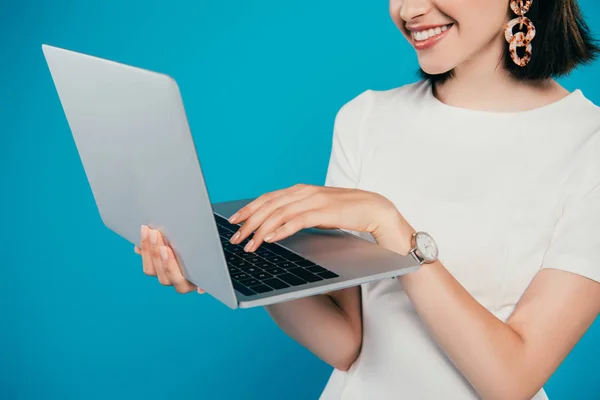 Vista recortada de la mujer elegante sonriente usando el ordenador portátil aislado en azul — Stock Photo