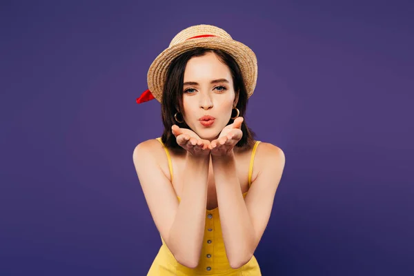 Pretty girl in straw hat blowing air kiss isolated on purple — Stock Photo