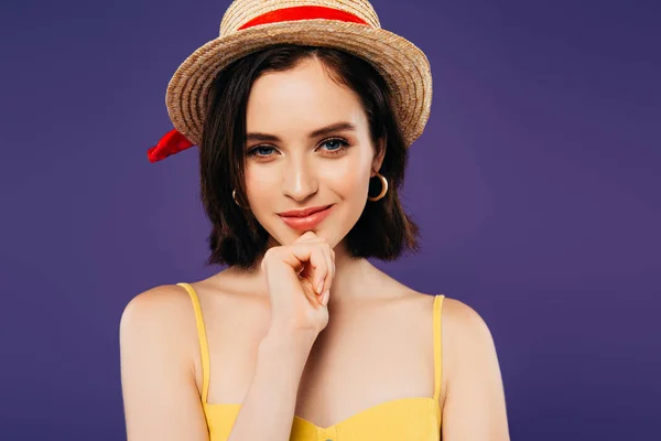 Fille souriante en chapeau de paille avec la main sur le menton isolé sur violet — Photo de stock