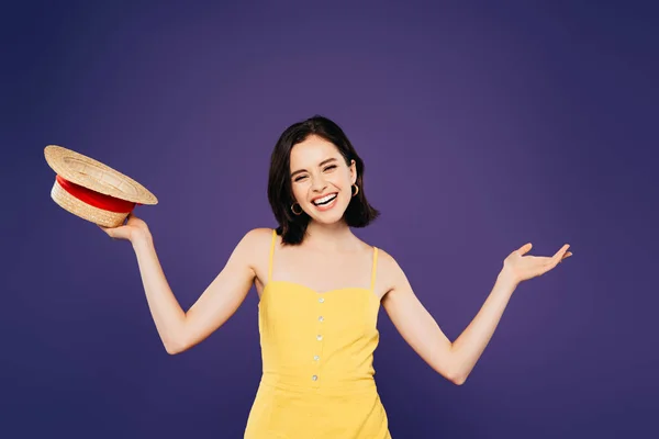 Smiling happy pretty girl holding straw hat isolated on purple — Stock Photo