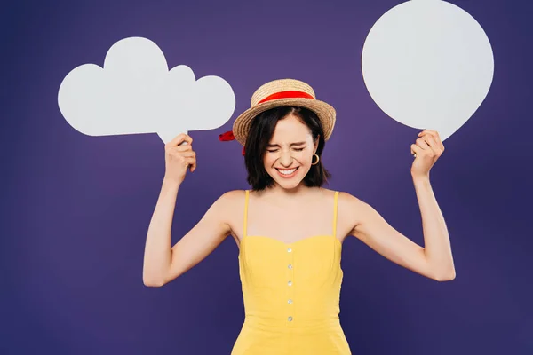 Chica feliz en sombrero de paja sosteniendo el pensamiento blanco vacío y burbujas de habla aislado en púrpura - foto de stock