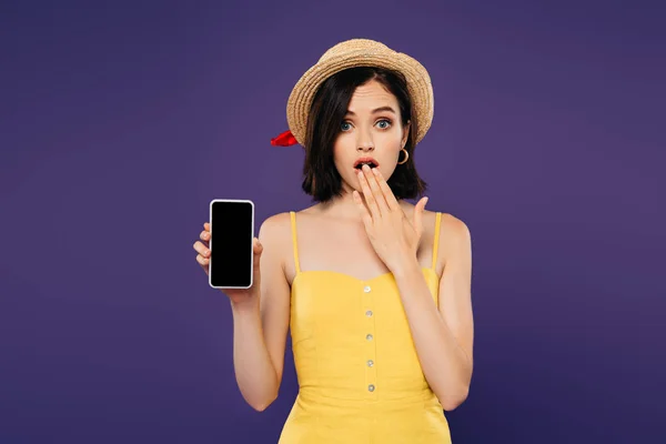 Chica en sombrero de paja mostrando gesto de idea y la celebración de teléfono inteligente con pantalla en blanco aislado en púrpura - foto de stock