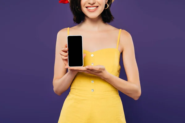 Vista cortada de menina sorridente segurando smartphone com tela em branco isolado em roxo — Fotografia de Stock