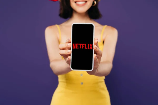 KYIV, UCRAINA - LUGLIO 3, 2019: focus selettivo della ragazza sorridente che presenta smartphone con l'app netflix isolata sul viola — Foto stock