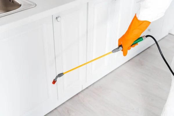 Vista ritagliata dello sterminatore in piedi uniforme con spray tossico in cucina — Foto stock