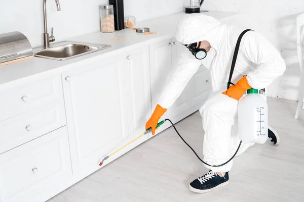 Exterminator holding toxic equipment near kitchen cabinet — Stock Photo