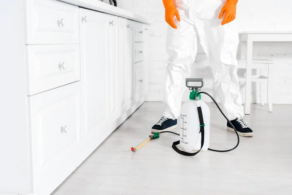 Vista recortada del hombre en uniforme de pie cerca de equipos tóxicos en la cocina - foto de stock