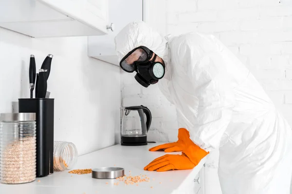 Sterminatore in maschera protettiva in piedi vicino armadio da cucina — Foto stock