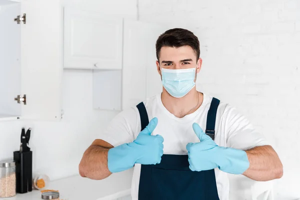 Exterminador en guantes de látex azul mostrando el pulgar hacia arriba - foto de stock