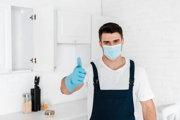 Homem de uniforme mostrando o polegar para cima enquanto em pé na cozinha — Fotografia de Stock