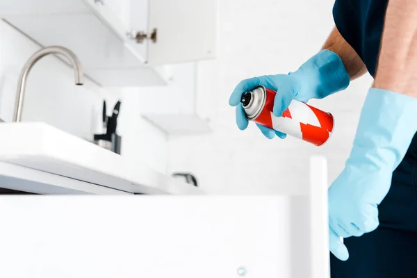 Cropped view of exterminator in latex gloves holding spray can near kitchen cabinet — Stock Photo